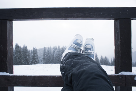 Legs skier in ski boots while relaxing after a day skiing. Mountain scenery awayの写真素材