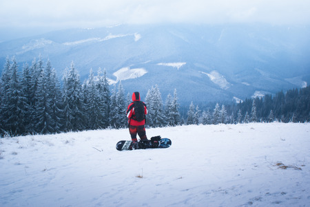Male snowboarder looks into the distance on snowy mountain slopesの写真素材