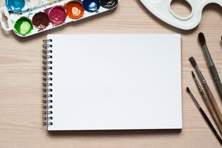 Paints, brushes, colored pencils and album - drawing tools on a deskの写真素材