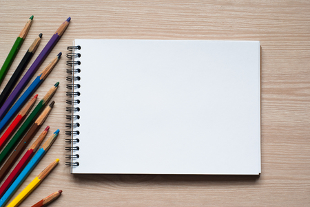 Colored pencils and album - drawing tools on a deskの写真素材