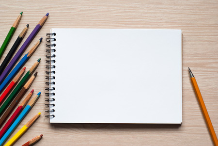 Colored pencils and album - drawing tools on a deskの写真素材