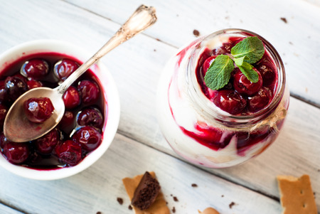 Sweet cherry cheesecake in a mason jar on wooden tableの写真素材