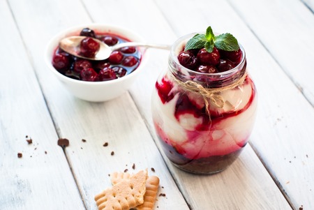 Sweet cherry cheesecake in a mason jar on wooden tableの写真素材