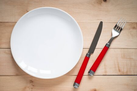 White plate, fork and knife.  View from above with copy space