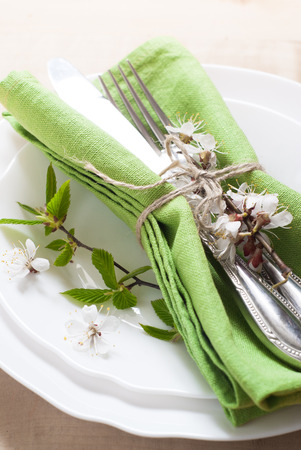 Spring table place setting with white plates, cutlery, napkin and flowers.の写真素材