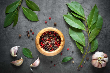 Herbs and spices selection. Bay leaves, pepper and garlic on slate background.