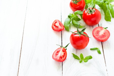 Vegetables background. Tomatoes, basil and garlic on white wooden table. Food background with copy space.の写真素材