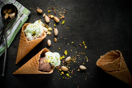 Ice cream with chocolate and pistachios on a dark slate background.の写真素材
