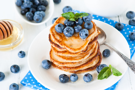 A stack of pancakes with blueberries and honey. White background.の写真素材
