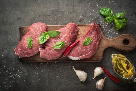 Raw meat. Raw beef chop on a cutting board with basil and spices. Top view with copy space.の写真素材