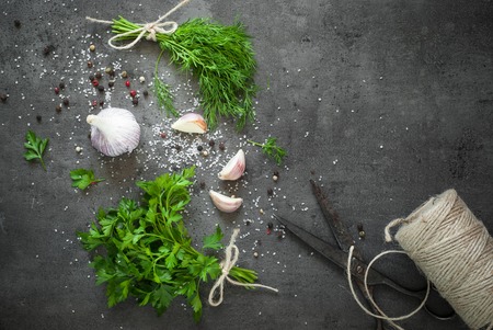 Herbs and spices at dark slate table. Parsley, dill, garlic and pepper. Ingredients for cooking.の写真素材