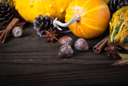Festive autumn background. Pumpkins, pine cones and leaves at dark wooden table.の写真素材