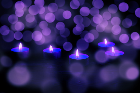 Some red candles at wooden table. Burning in the night.の写真素材