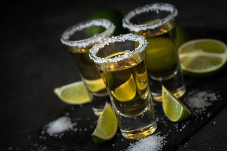 Tequila shot with lime and sea salt on black tableの写真素材