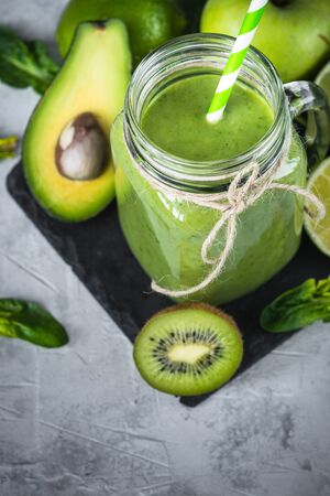 Healthy green smoothie in mason jar and ingredients. Superfoods, detox, diet, healthy food. Lime, apple, spinach, avocado and limeの写真素材