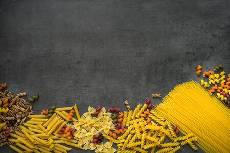 Various types of pasta - spaghetti, penne, fusilli, colored vegetables pasta.  Top view with copy space.の写真素材