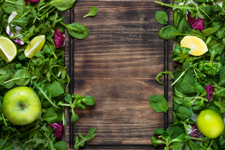 Green food background. Salad ingredients on table with copy space and cutting board for your text. Healthy food and diet concept.の写真素材