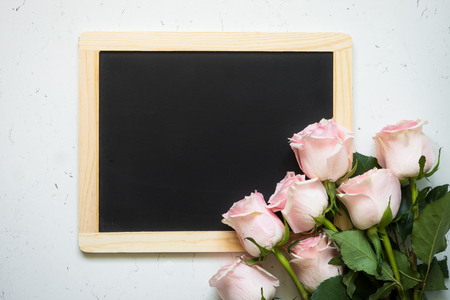 Pink rose and chalkboard at white stone table. Top view copy space. Flower background.の写真素材