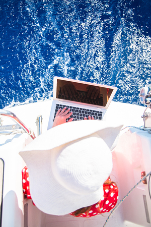 Beautiful yong Woman freelancer on a sailboat with a laptop computer. Freelance work conceptの写真素材
