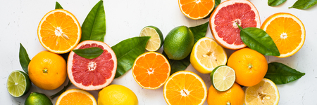 Fresh citrus fruit assortment on white table. Fruit food background. Long banner format.