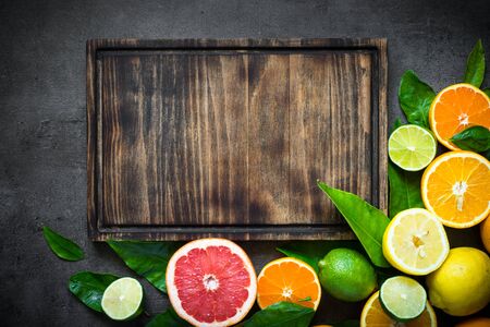 Fresh citrus fruit assortment. Whole and sliced citrus fruit on black slate table. Fruit food background. Top view copy space.の写真素材