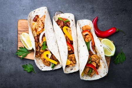 Mexican taco with meat beans and vegetables at black stone table. Latin american food. Top view.の写真素材