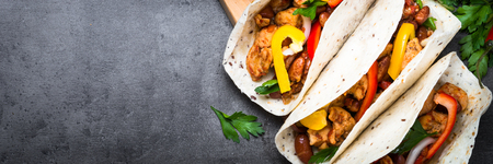 Mexican taco with meat beans and vegetables at black stone table. Latin american food. Long banner format.の写真素材