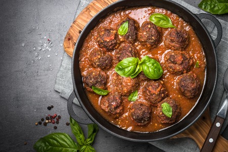 Meatballs in tomato sauce in a cast-iron frying pan on a black background. Top view copy space.の写真素材