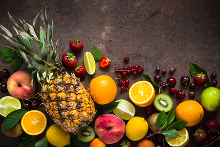 Fruit and berries on dark stone table. Top view with copy space.  Pineapple, citrus fruit and berry mix.の写真素材