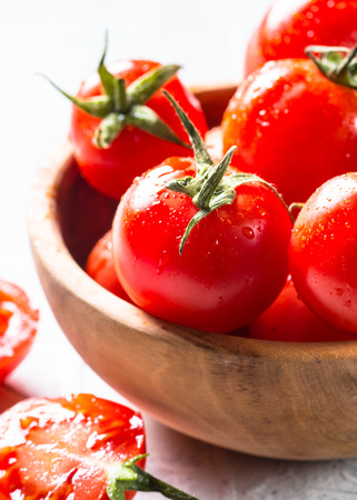 Tomatoes in wooden bowl. Fresh wet cherry tomato. Close up.の写真素材