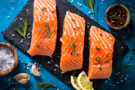 Fresh fish. Salmon uncooked fillet with lemon, sea salt and rosemary. Top view.の写真素材