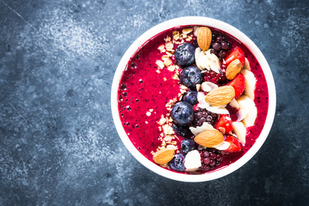 Smoothie bowl from fresh berries, nuts and granola. Top view on dark stone table.の写真素材