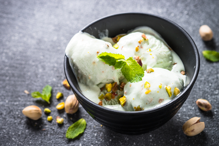 Pistachios ice cream in bowl on black stone table.の写真素材