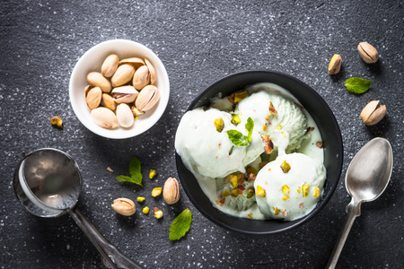 Pistachios ice cream in bowl on black stone table.の写真素材