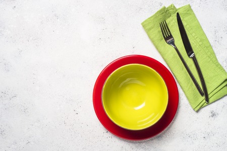 Colored dinnerware - plate, cutlery and napkin on light stone taの写真素材