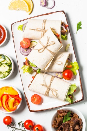 Burritos tortilla wraps with beef and vegetables on white background.の写真素材