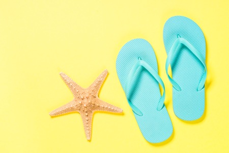 Blue flip flops and starfish on yellow background.の写真素材