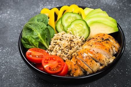 Buddha bowl quinoa salad with chicken and vegetables on black.の写真素材