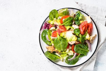Green salad with chicken and vegetables on white stone table. Top view with copy space.の写真素材