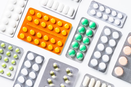 Pills in a blister and vitamins on white background flatlay isolated. Medical  pharmacy concept.