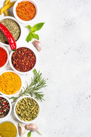 Set of spices and fresh herbs on white stone table. Curry, rosemary, turmeric, peppercorn, paprika, basil, cinnamon, cardamom and other. Top View with copy space.の写真素材