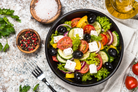Greek salad in black plate on the table.の写真素材