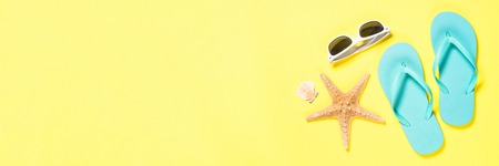 Blue flip flops, swimsuit, sunglasses and starfish on yellow background.の写真素材