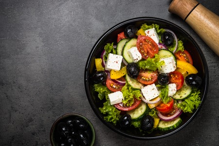 Greek salad in black plate on the table.の写真素材