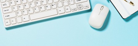 Office desk with keyboard and notebook on blue.の写真素材