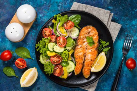 Grilled salmon fish steak with fresh vegetables salad. Keto diet food. Top view with copy space.の写真素材