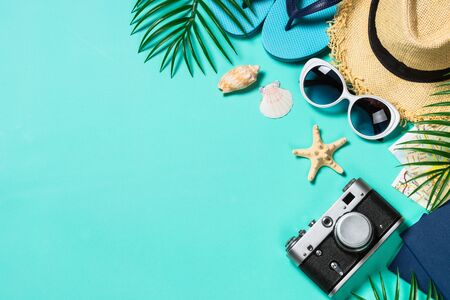 Summer holiday flat lay background. Old film camera, hat, map, sunglasses and palm leaves on blue background. Top view with copy space.の写真素材