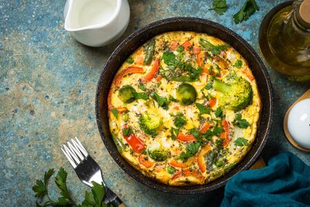 Frittata with fresh vegetables. Baked omelette with broccoli, paprika, brussels sprouts, green beans and herbs. Top view with copy space.の写真素材