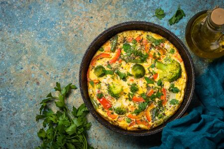 Frittata with fresh vegetables. Baked omelette with broccoli, paprika, brussels sprouts, green beans and herbs. Top view with copy space.の写真素材