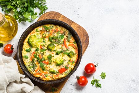 Frittata with fresh vegetables. Baked omelette with broccoli, paprika, brussels sprouts, green beans and herbs. Top view with copy space on white table.の写真素材